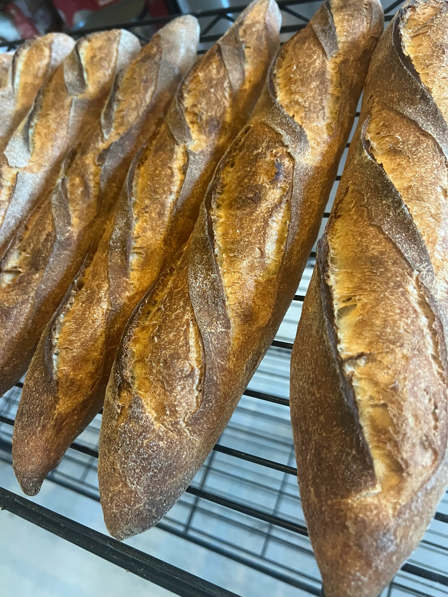 Fresh baked baguettes cooling on a rack
